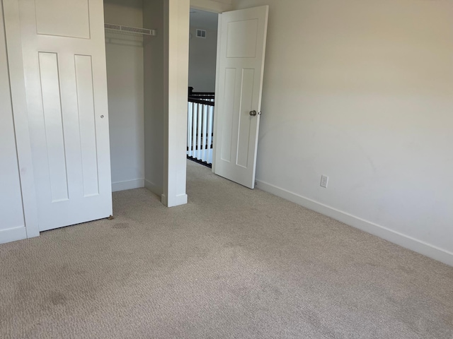 unfurnished bedroom with a closet and light colored carpet