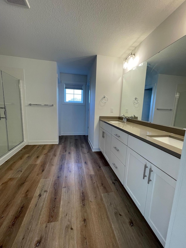 bathroom featuring vanity, an enclosed shower, a textured ceiling, and wood-type flooring