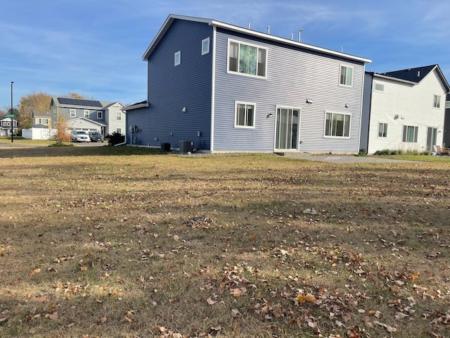 back of property with central AC unit and a lawn