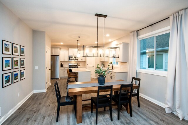 dining area with sink, a chandelier, and dark hardwood / wood-style flooring