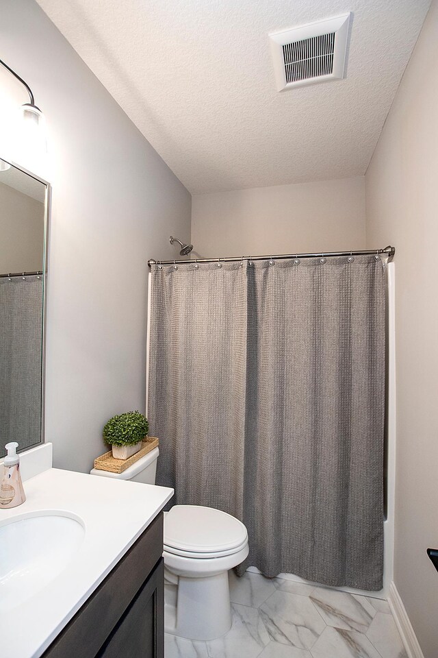 full bathroom featuring vanity, toilet, shower / bath combo with shower curtain, and a textured ceiling