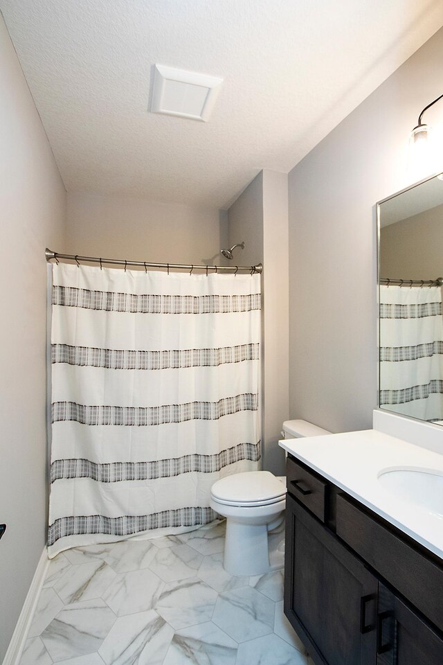 bathroom with vanity, toilet, curtained shower, and a textured ceiling