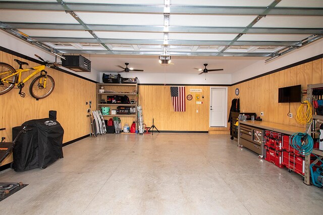 garage featuring a garage door opener, ceiling fan, and wooden walls