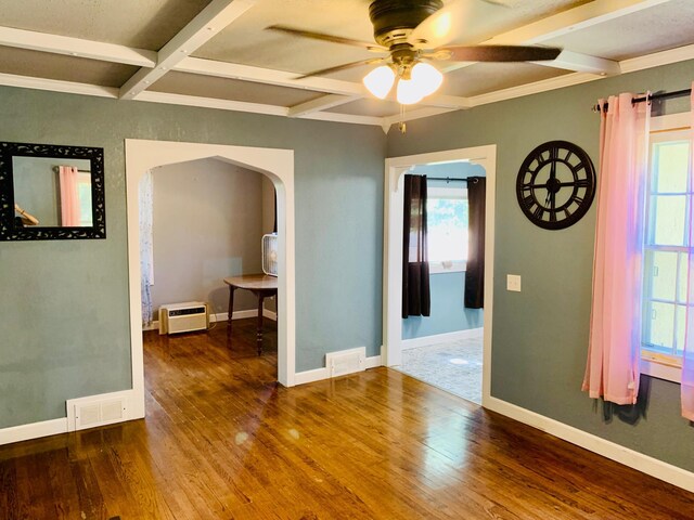 empty room with ceiling fan, coffered ceiling, wood-type flooring, and beam ceiling