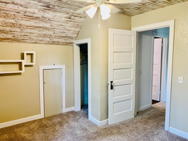 unfurnished bedroom featuring wooden ceiling, carpet, a closet, lofted ceiling, and ceiling fan