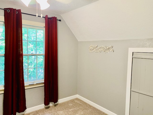 additional living space with lofted ceiling, light colored carpet, ceiling fan, and a textured ceiling