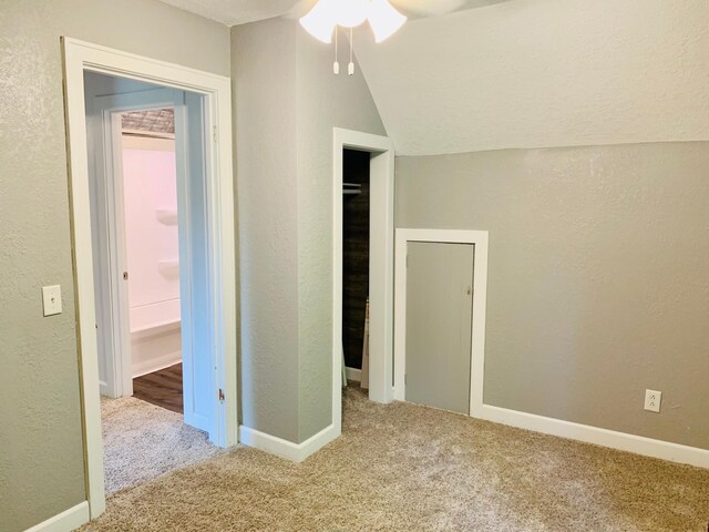 unfurnished bedroom featuring lofted ceiling, carpet flooring, and a textured ceiling