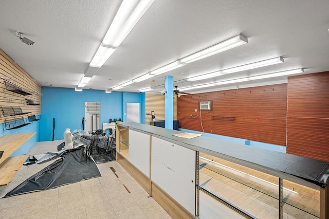 interior space with wood walls, a textured ceiling, and ceiling fan