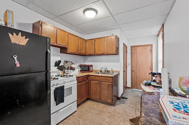 kitchen with light tile patterned floors, a drop ceiling, sink, and black appliances