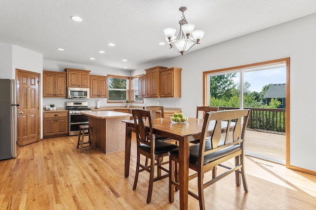 dining area featuring sink, a chandelier, light hardwood / wood-style floors, and a textured ceiling