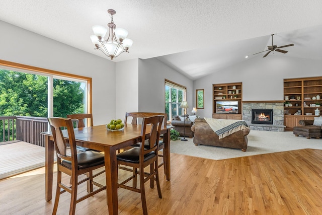 dining room featuring a fireplace, a textured ceiling, light wood-type flooring, and built in shelves