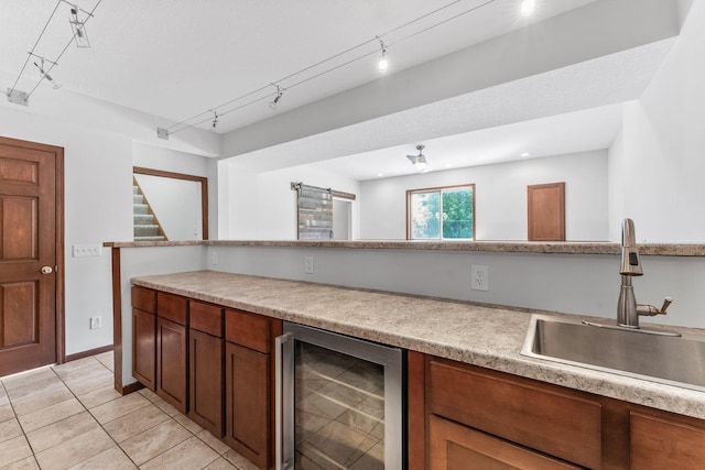 kitchen with sink, beverage cooler, light tile patterned floors, a barn door, and track lighting