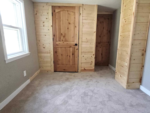 unfurnished bedroom featuring wood walls and light carpet