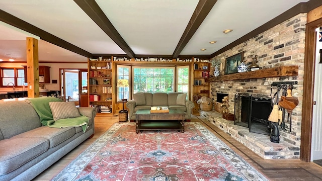 living room with beamed ceiling, a brick fireplace, and wood-type flooring