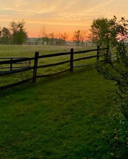 gate at dusk featuring a yard and a rural view