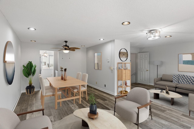 living room featuring wood-type flooring, ceiling fan, and a textured ceiling