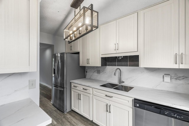 kitchen with hanging light fixtures, sink, appliances with stainless steel finishes, light stone countertops, and dark hardwood / wood-style flooring