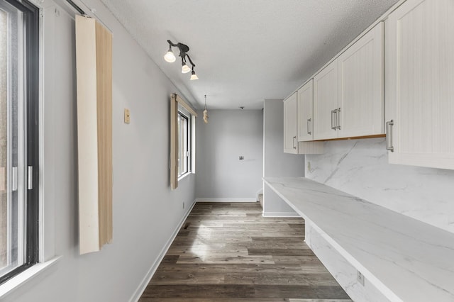 interior space featuring track lighting, a textured ceiling, and dark hardwood / wood-style flooring