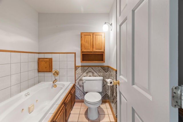 bathroom with a washtub, tile walls, toilet, and tile patterned floors