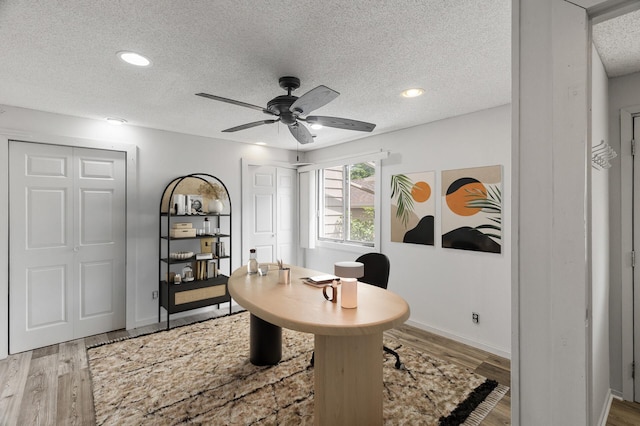 office area with light hardwood / wood-style floors, ceiling fan, and a textured ceiling