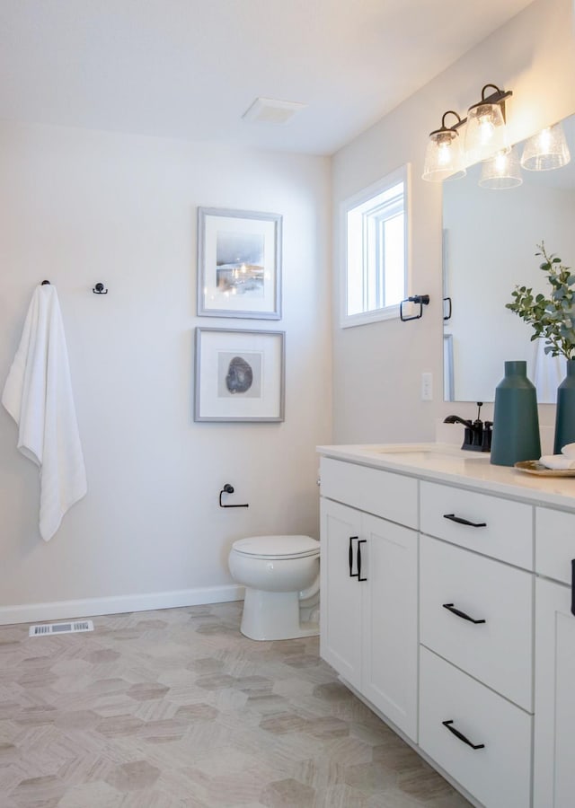 bathroom featuring visible vents, vanity, toilet, and baseboards