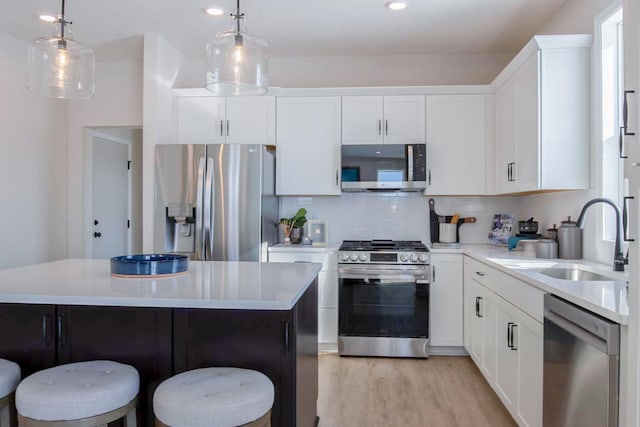 kitchen with a breakfast bar area, stainless steel appliances, a sink, and light countertops