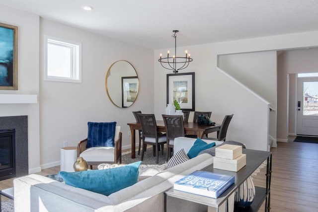 living area featuring recessed lighting, an inviting chandelier, a glass covered fireplace, wood finished floors, and baseboards