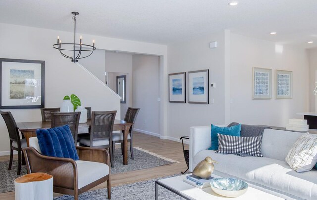 living area with light wood finished floors, baseboards, a chandelier, and recessed lighting