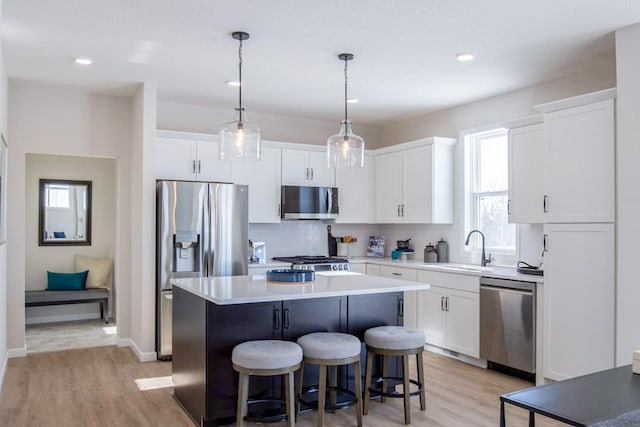 kitchen featuring stainless steel appliances, white cabinetry, a sink, and a kitchen island