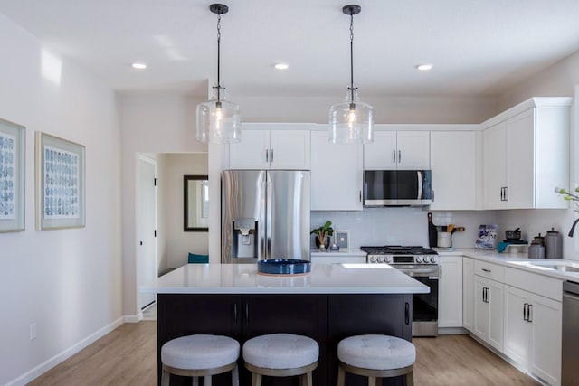 kitchen with light wood-style flooring, a kitchen island, appliances with stainless steel finishes, tasteful backsplash, and a kitchen bar