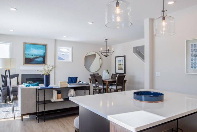 kitchen with light countertops, recessed lighting, a glass covered fireplace, and light wood-style floors