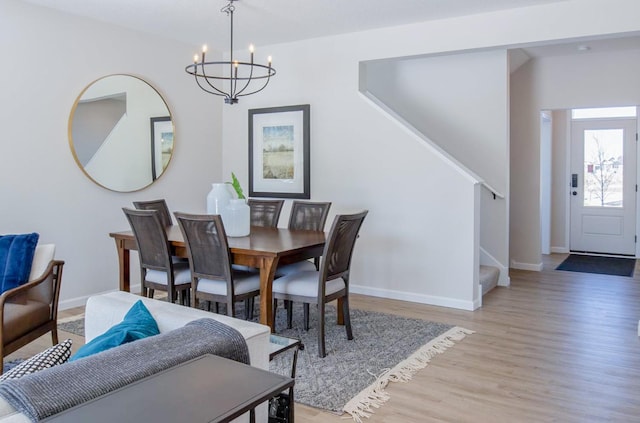 dining space with baseboards, a notable chandelier, stairway, and light wood finished floors