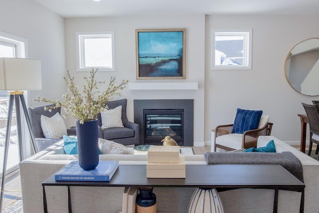 living area with a wealth of natural light, a glass covered fireplace, and baseboards