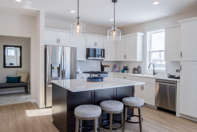 kitchen with appliances with stainless steel finishes, white cabinets, a sink, and a center island