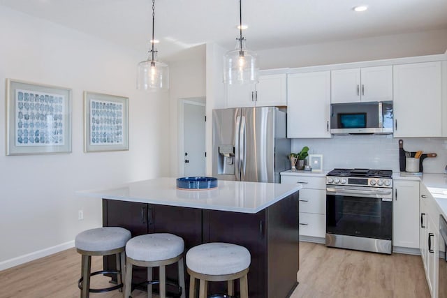 kitchen featuring light wood finished floors, tasteful backsplash, white cabinets, a kitchen breakfast bar, and stainless steel appliances