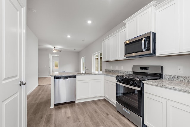 kitchen featuring white cabinetry, sink, kitchen peninsula, light hardwood / wood-style floors, and appliances with stainless steel finishes