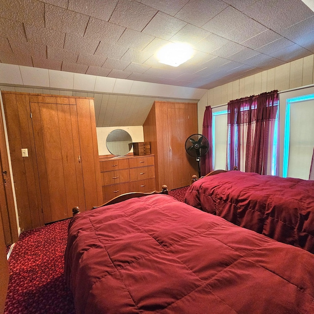 bedroom featuring carpet flooring and wooden walls