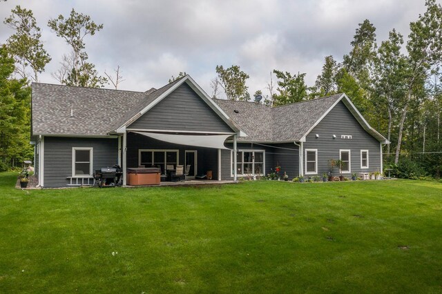 rear view of house featuring a patio area, a hot tub, and a lawn