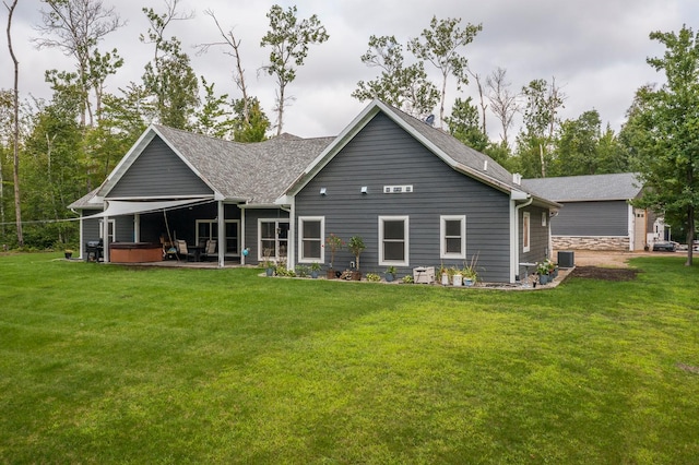 back of property featuring a hot tub, a yard, and a patio