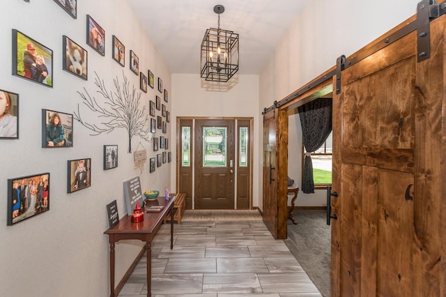 entrance foyer featuring a barn door, a chandelier, and dark carpet