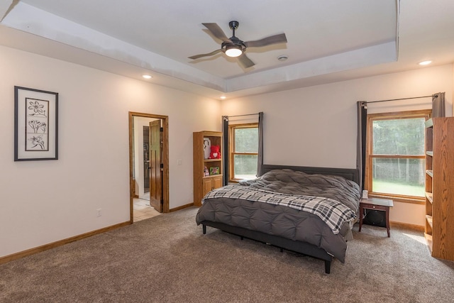 bedroom featuring ceiling fan, light colored carpet, and a raised ceiling