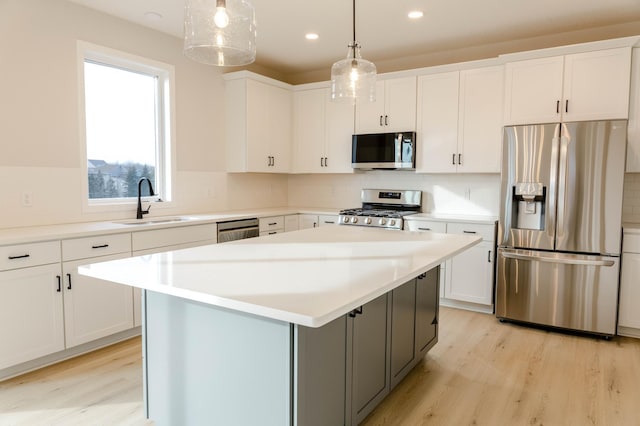 kitchen with white cabinets, a center island, appliances with stainless steel finishes, and pendant lighting