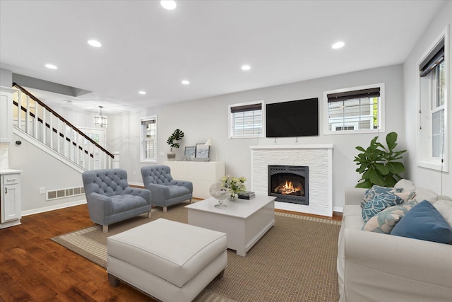 living room featuring dark hardwood / wood-style flooring, a wealth of natural light, and a stone fireplace