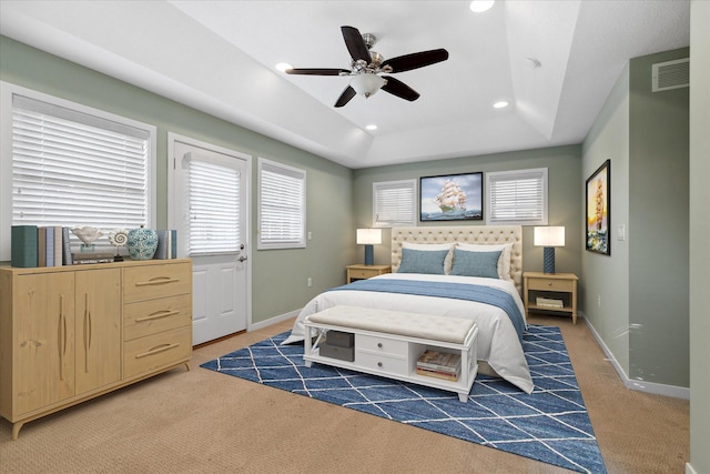 bedroom featuring ceiling fan, dark colored carpet, and a tray ceiling