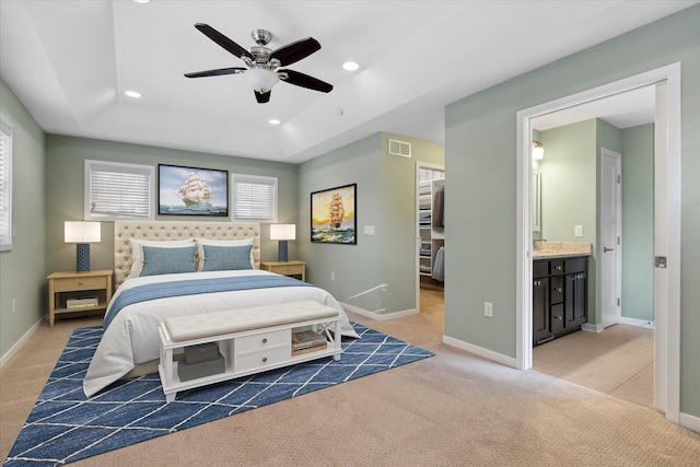 bedroom featuring ensuite bathroom, ceiling fan, a closet, and light colored carpet