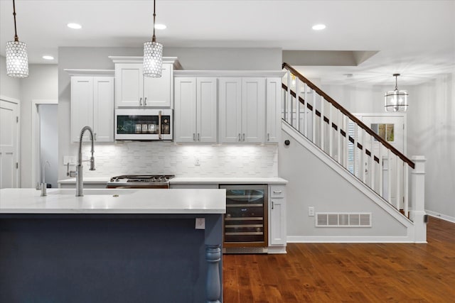 kitchen with white cabinetry, wine cooler, backsplash, decorative light fixtures, and dark hardwood / wood-style flooring