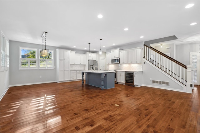 kitchen featuring pendant lighting, stainless steel appliances, white cabinetry, and wine cooler