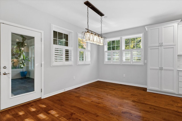 unfurnished dining area with a chandelier and dark hardwood / wood-style floors