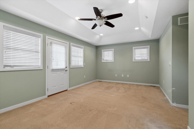 carpeted empty room with ceiling fan and a tray ceiling