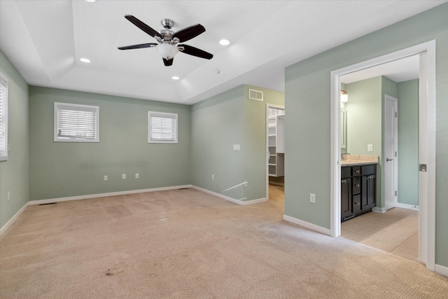 interior space with ensuite bathroom, ceiling fan, a spacious closet, light colored carpet, and a closet